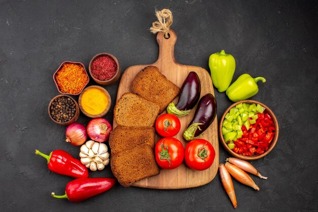 Vue de dessus des miches de pain noir avec des légumes frais sur fond sombre plat plat santé repas