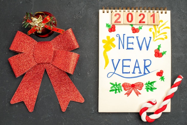 Vue de dessus mignon arc rouge avec bloc-notes écrit nouvel an