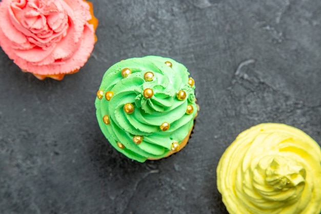 Photo gratuite vue de dessus de mini cupcakes colorés en rangée diagonale sur une surface sombre