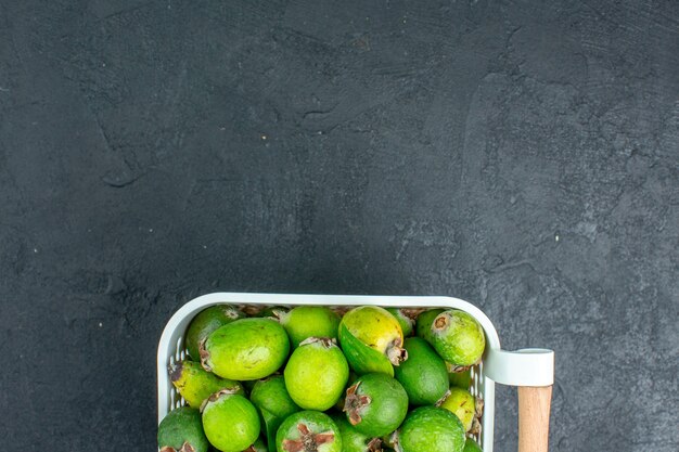 Vue de dessus à moitié frais feijoas sur panier en plastique sur l'espace libre de table sombre