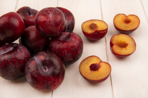 Vue de dessus de la moitié juteuse et des pluots entiers isolés sur un mur en bois beige