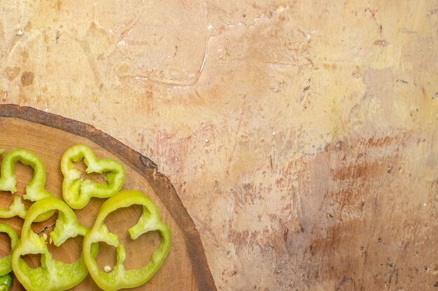 Vue de dessus de la moitié des poivrons coupés en morceaux sur une planche de bois d'arbre ronde sur fond ambré