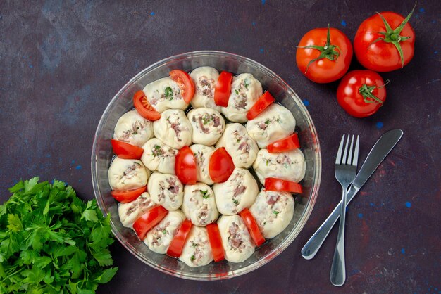 Vue de dessus des morceaux de pâte crue avec de la viande hachée et des tomates rouges fraîches sur un repas sombre cuisine couleur nourriture photo plat cuisine