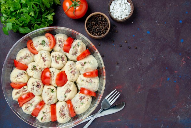 Vue de dessus des morceaux de pâte crue avec de la viande hachée et des tomates rouges fraîches sur un repas sombre cuisine salade couleur plat de nourriture cuisine photo