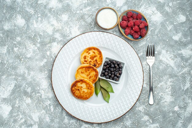 Vue de dessus des muffins sucrés avec des baies à l'intérieur de la plaque sur la surface légère