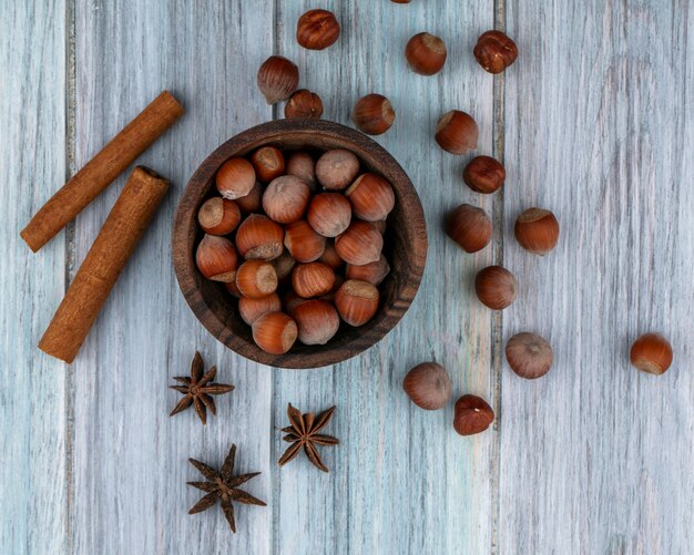 Vue de dessus noisette dans un bol avec de la cannelle sur fond gris