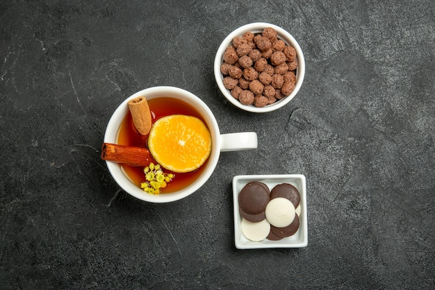 Vue de dessus noisettes au chocolat bols de chocolat et noisettes une tasse de thé au cinabre et au citron sur la surface sombre