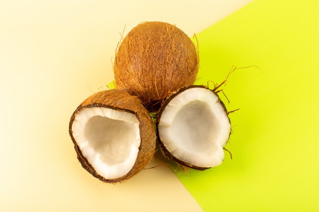 Une vue de dessus de noix de coco entières et tranchées moelleux frais laiteux isolé sur la couleur crème-pistache