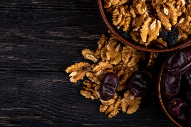 Vue de dessus des noix dans un bol et des dattes séchées sucrées sur bois