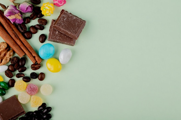 Vue de dessus des noix dans des bonbons au chocolat marmelade grains de café et des bâtons de cannelle sur la table avec copie espace