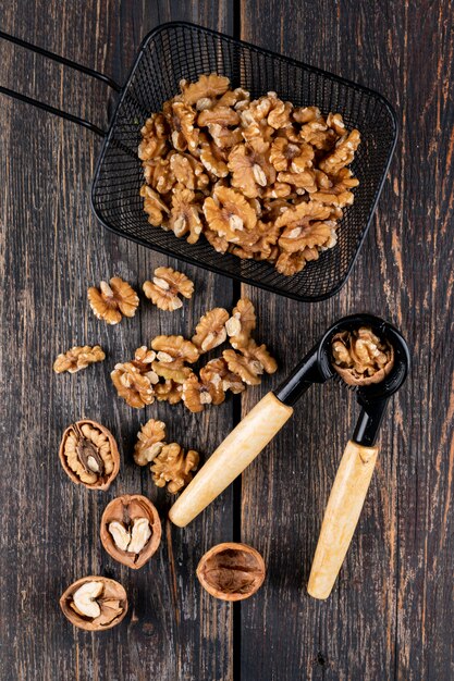 Vue de dessus des noix dans un panier noir avec casse-noisette sur vertical en bois