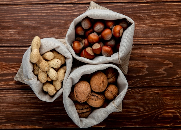 Vue de dessus des noix dans des sacs d'arachides de noix et de noisettes en coque sur fond de bois