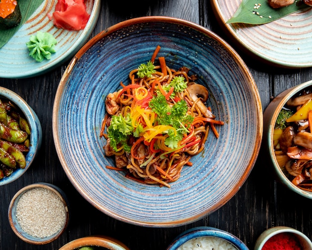 Photo gratuite vue de dessus des nouilles sautées aux légumes et crevettes dans une assiette sur la table en bois