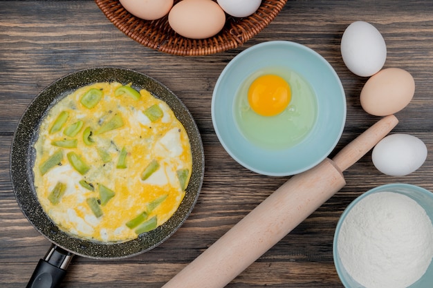 Photo gratuite vue de dessus de l'oeuf au plat sur une casserole avec du poivre avec du blanc d'oeuf et du jaune sur une plaque bleue sur un fond en bois