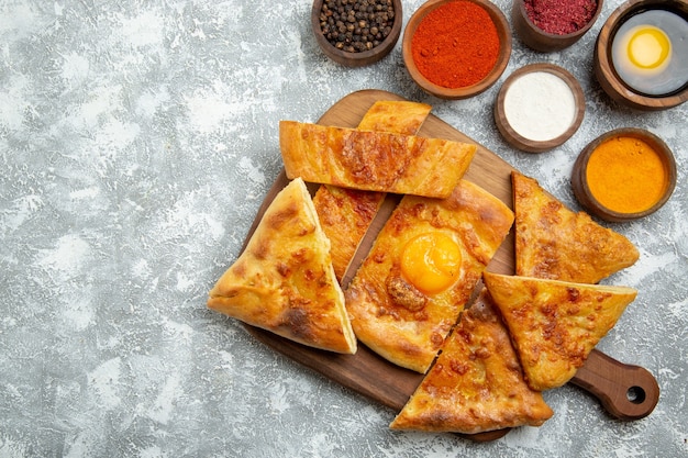 Vue de dessus oeuf en tranches cuire de délicieuses pâtisseries avec des assaisonnements sur fond blanc clair pâtisserie cuire la pâte nourriture repas pizza