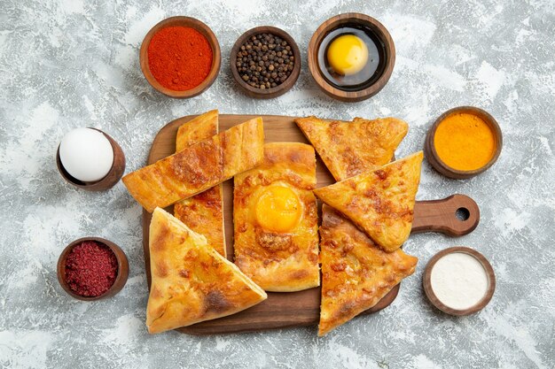 Vue de dessus oeuf en tranches cuire de délicieuses pâtisseries avec des assaisonnements sur fond blanc pâtisserie cuire la pâte nourriture repas pizza