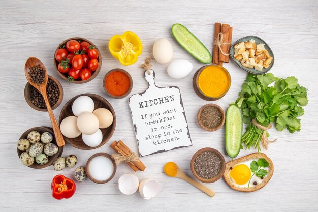 Vue de dessus des œufs blancs frais avec des légumes et des assaisonnements sur un fond blanc couleur de la nourriture déjeuner mûr salade petit déjeuner