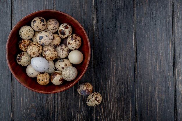 Vue de dessus des oeufs de caille sur un bol en bois sur un fond en bois avec espace copie