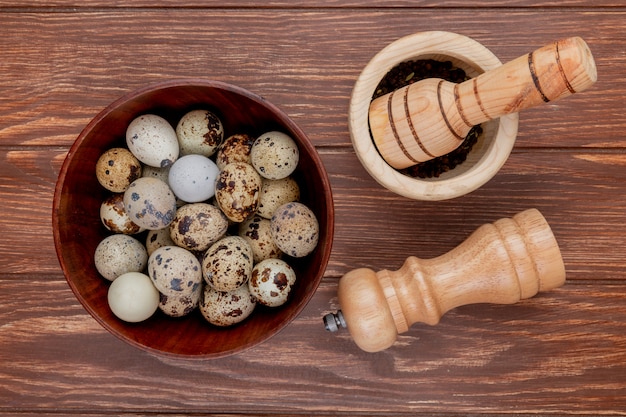 Vue de dessus des œufs de caille sur un bol en bois avec mortier en bois et pilon sur un fond en bois