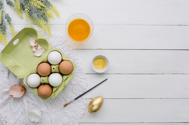 Vue de dessus des oeufs en carton pour Pâques et colorant avec pinceau