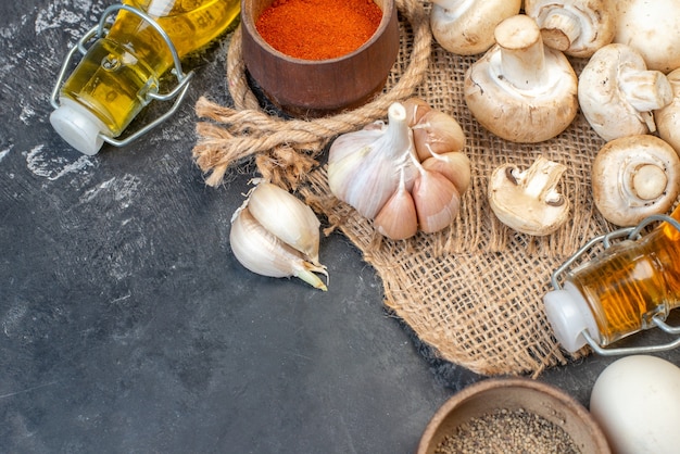 Vue de dessus des œufs de champignons frais bouteille d'huile poudre de poivre rouge dans un petit bol d'ail sur un lieu de copie de table gris