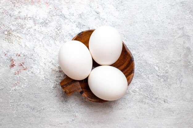 Vue de dessus des oeufs crus entiers sur la surface blanche des oeufs crus petit déjeuner nourriture repas