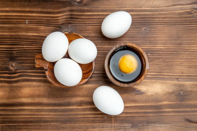 Vue de dessus des oeufs crus entiers sur la surface en bois brun repas petit déjeuner alimentaire oeuf en bois