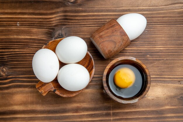 Vue de dessus oeufs crus produits entiers sur la surface brune oeuf nourriture repas déjeuner déjeuner pain santé