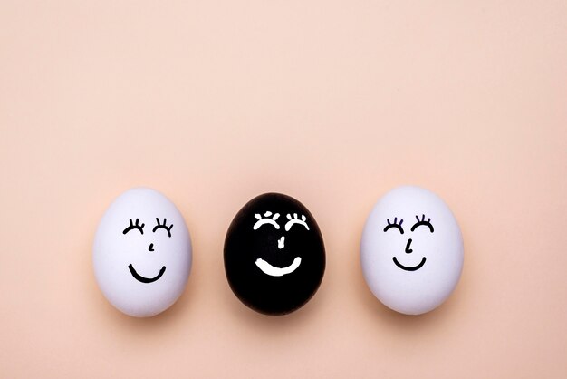 Vue de dessus des œufs de différentes couleurs avec des visages pour le mouvement des vies noires