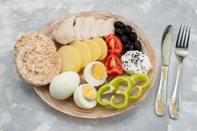 Vue de dessus oeufs durs avec poitrines d'olives assaisonnements craquelins et tomates sur gris, petit-déjeuner repas végétarien