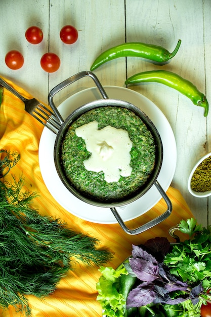 Vue de dessus des oeufs frits kuku traditionnels azerbaïdjanais aux herbes servis avec du yaourt aigre dans une casserole