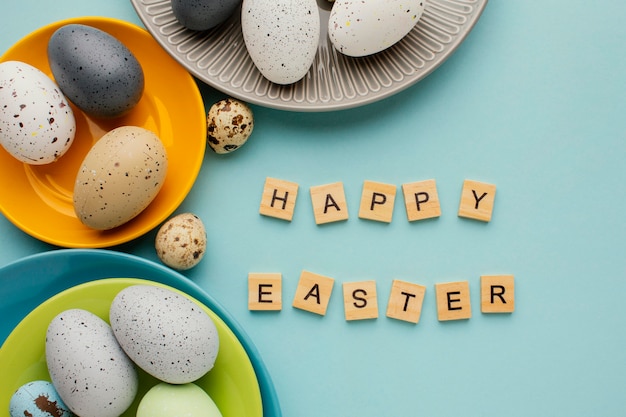 Photo gratuite vue de dessus des oeufs de pâques colorés sur plusieurs assiettes avec message d'accueil