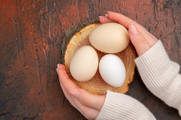 Vue de dessus des œufs de poule blancs sur une table sombre repas animal photo crue nourriture de ferme petit-déjeuner