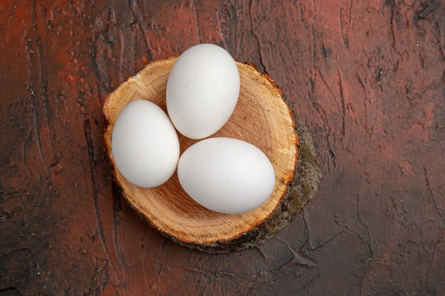 Vue de dessus des œufs de poule blancs sur une table sombre repas d'animaux photo couleur ferme brute