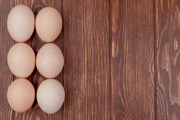 Photo gratuite vue de dessus des œufs de poule frais disposés sur un fond en bois avec espace copie