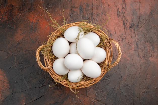 Photo gratuite vue de dessus des œufs de poule frais à l'intérieur du panier sur une table sombre