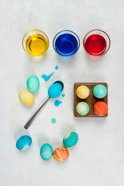 Vue de dessus des oeufs pour Pâques avec de la peinture dans des verres et une cuillère