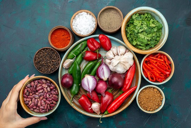 Vue de dessus les oignons et l'ail avec des poivrons rouges haricots verts sur le repas de produit ingrédient alimentaire table sombre