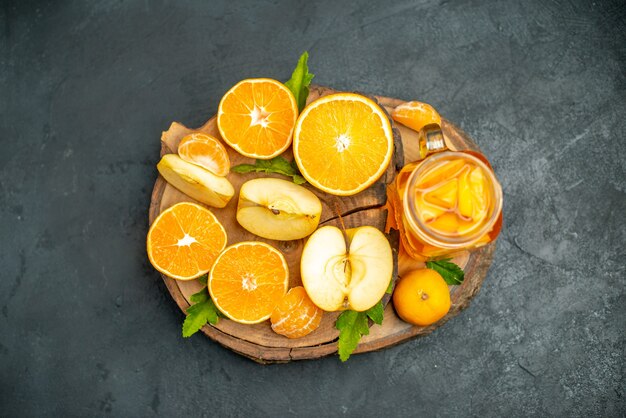 Vue de dessus des oranges coupées et des pommes coupées en orange sur fond sombre