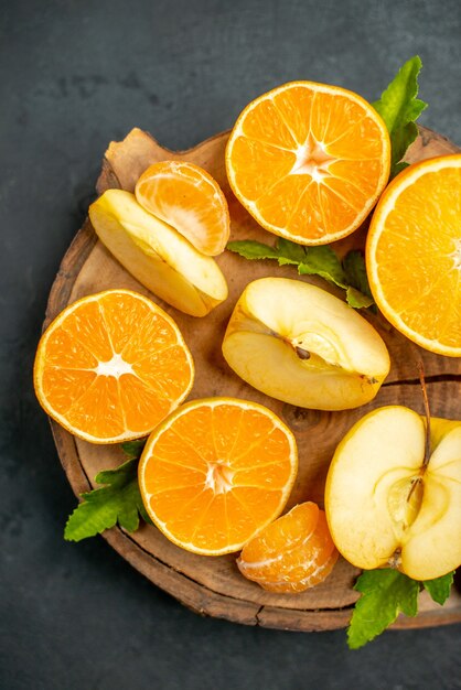 Vue de dessus des oranges coupées et des pommes coupées en orange sur fond sombre