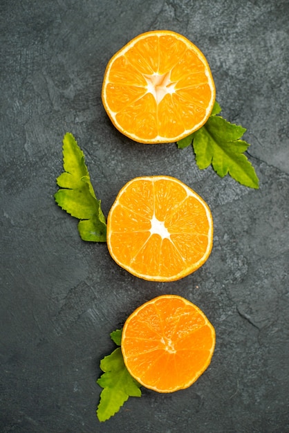 Vue de dessus des oranges coupées en rangée verticale sur une surface sombre