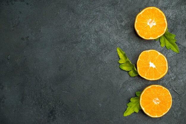 Vue de dessus des oranges coupées en rangée verticale sur une surface sombre