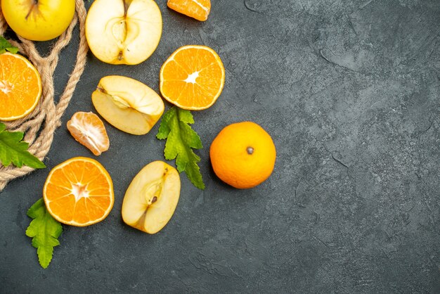 Vue de dessus des oranges et des pommes coupées sur une surface sombre