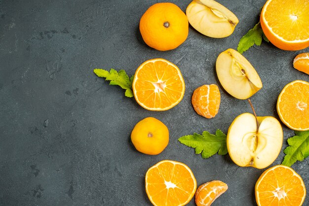 Vue de dessus des oranges et des pommes coupées sur une surface sombre