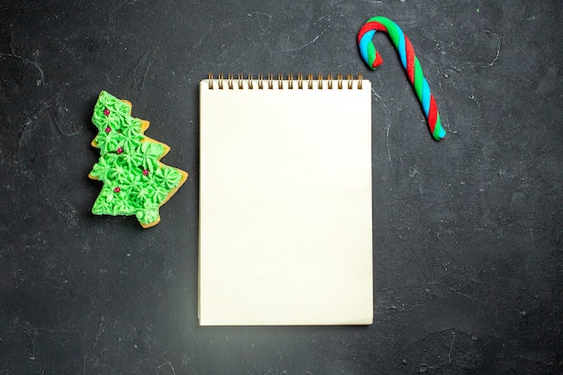 Photo gratuite vue de dessus un ordinateur portable bonbons de noël et biscuit d'arbre de noël sur fond sombre espace libre