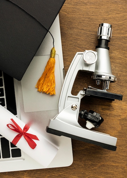 Vue de dessus de l'ordinateur portable avec microscope et capuchon académique