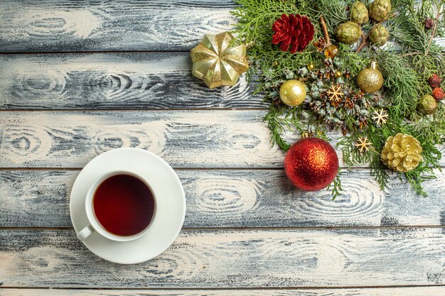 Vue de dessus des ornements de Noël une tasse de branches de sapin à thé sur fond de bois espace libre