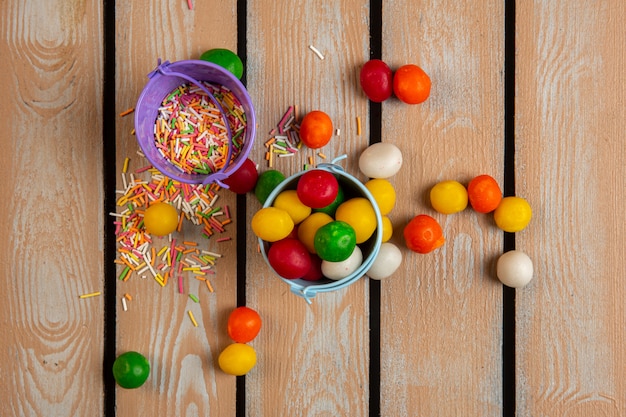 Photo gratuite vue de dessus de paillettes colorées et de bonbons dans de petits seaux