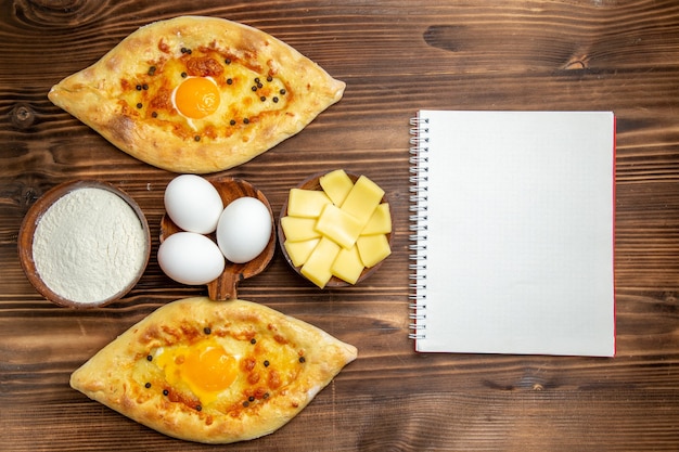 Photo gratuite vue de dessus pains aux œufs cuits au four fraîchement sortis du four sur le bureau en bois brun pâte petit-déjeuner pain aux œufs