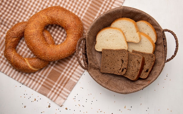 Vue De Dessus Des Pains Comme Bagel Turc Sur Tissu Et Panier Avec Des Tranches De Pain De Seigle Blanc Sur Fond Blanc